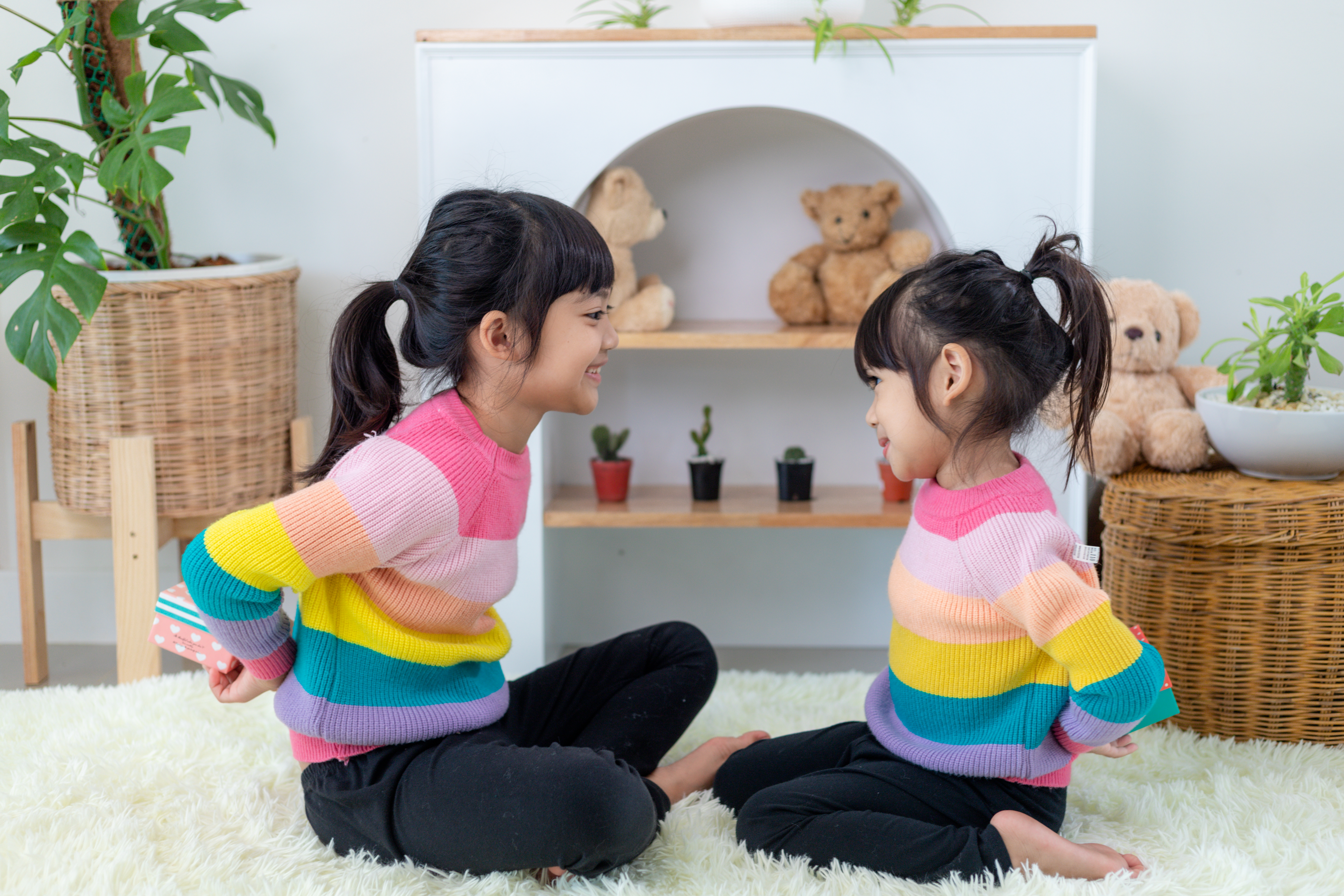 zwei schwestern sitzen auf einem teppich